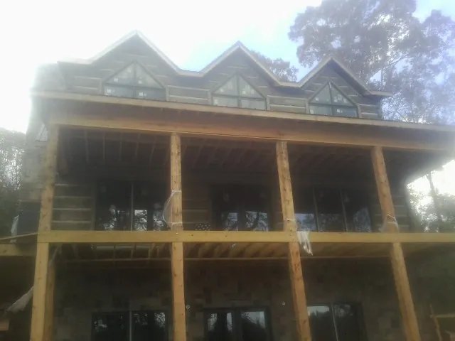 Dormers and porch framing on a large log home under construction — Roof Coating work by our crew in Richmond